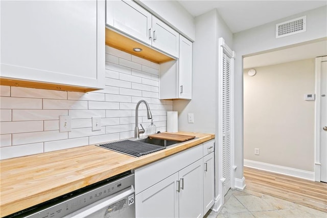 kitchen featuring dishwasher, sink, decorative backsplash, and white cabinetry