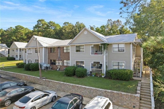 view of front of property featuring a front yard and a balcony