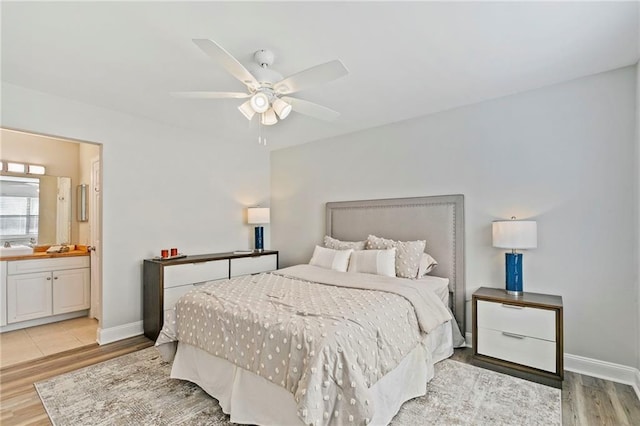 bedroom with ensuite bathroom, light hardwood / wood-style flooring, and ceiling fan