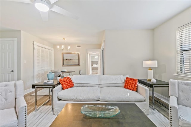 living room featuring ceiling fan with notable chandelier and light hardwood / wood-style flooring