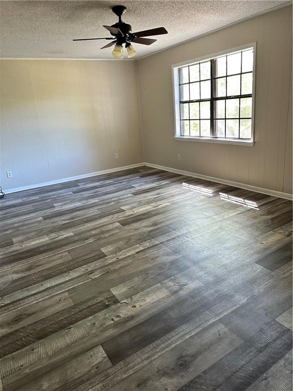 unfurnished room featuring ceiling fan, a textured ceiling, and dark wood-type flooring