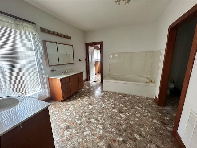 bathroom with a bathing tub, vanity, and toilet