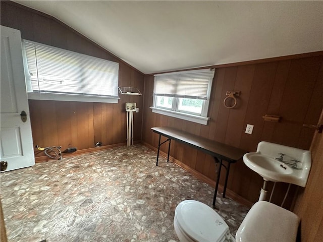 bathroom featuring wooden walls, vaulted ceiling, and toilet