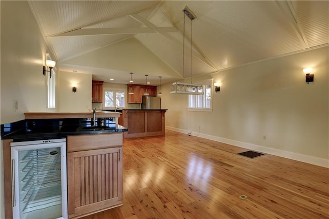 kitchen featuring sink, wine cooler, decorative light fixtures, light hardwood / wood-style floors, and stainless steel refrigerator