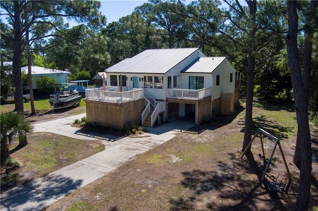 view of front of home featuring driveway, metal roof, and stairway