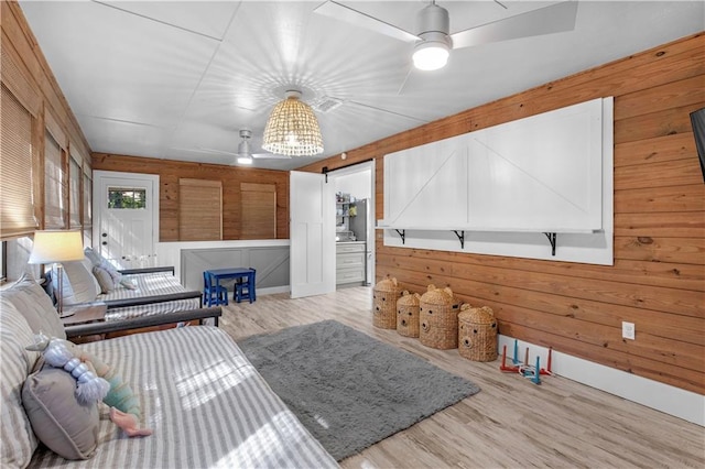 living room featuring wood walls, ceiling fan, and wood finished floors