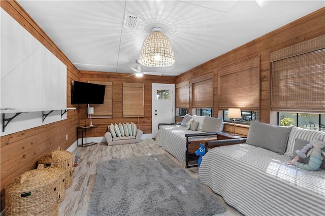 bedroom with a chandelier, wooden walls, wood finished floors, and visible vents