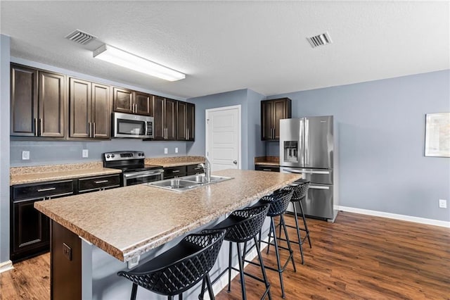 1951 Stonepine Dr, Semmes, AL 36575 - kitchen featuring stainless steel appliances, a kitchen bar, dark brown cabinets, dark wood finished floors, and a textured ceiling