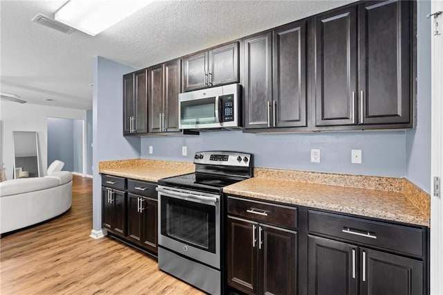 1951 Stonepine Dr, Semmes, AL 36575 - kitchen featuring appliances with stainless steel finishes, light wood-style flooring, light countertops, and a textured ceiling