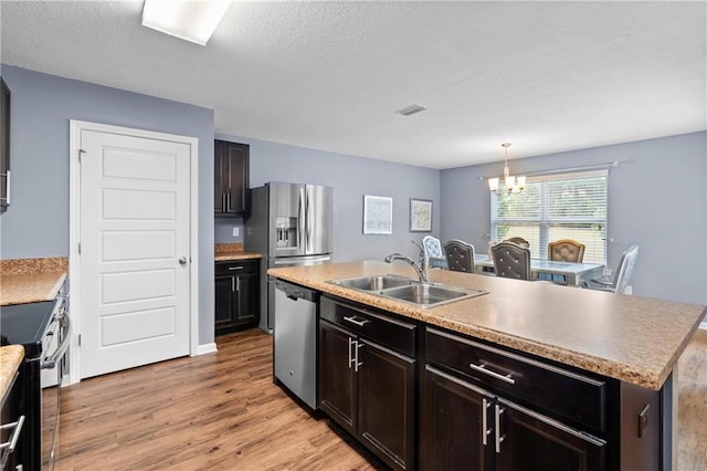 1951 Stonepine Dr, Semmes, AL 36575 - kitchen featuring stainless steel appliances, a chandelier, light wood-style flooring, a center island with sink, and light countertops