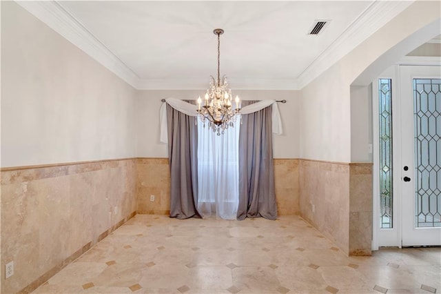 unfurnished dining area featuring ornamental molding, tile walls, and a chandelier