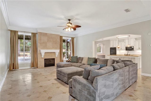 living room with ceiling fan, crown molding, a high end fireplace, and sink