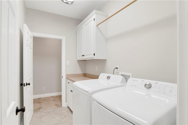 clothes washing area featuring washer and clothes dryer, cabinets, and light tile patterned floors