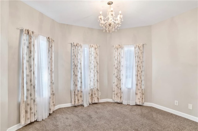 carpeted empty room with a chandelier