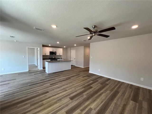 unfurnished living room featuring a textured ceiling, dark wood-type flooring, and ceiling fan