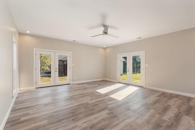 empty room with ceiling fan, french doors, and light wood-type flooring