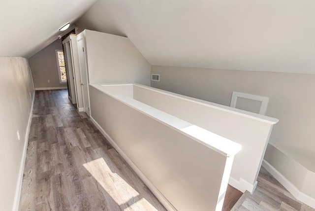 corridor with hardwood / wood-style floors and lofted ceiling