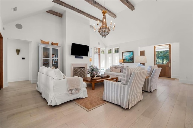 living room featuring a healthy amount of sunlight, high vaulted ceiling, light hardwood / wood-style flooring, and a notable chandelier