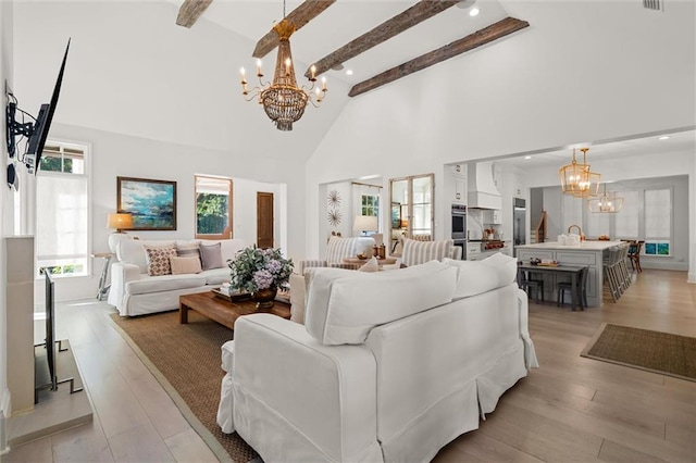 living room featuring an inviting chandelier, high vaulted ceiling, light hardwood / wood-style floors, and beamed ceiling