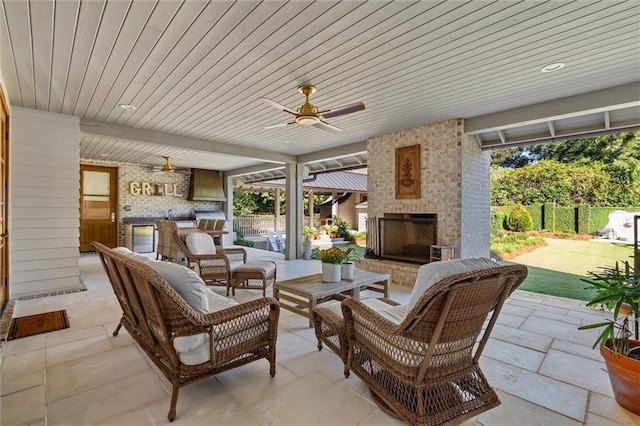 view of patio featuring ceiling fan, an outdoor kitchen, and an outdoor living space with a fireplace