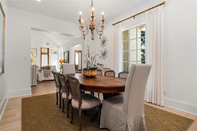 dining room featuring lofted ceiling, light hardwood / wood-style flooring, and a notable chandelier