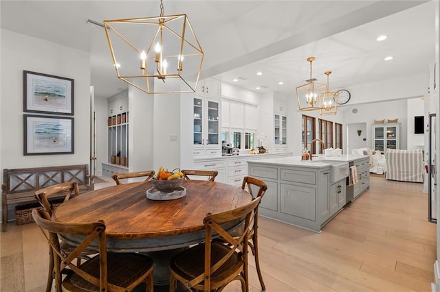 dining space featuring an inviting chandelier, sink, and light hardwood / wood-style flooring