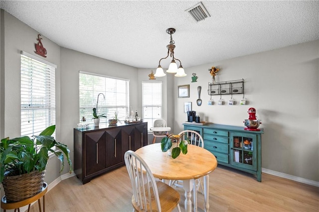 dining room with a textured ceiling, light hardwood / wood-style flooring, and a healthy amount of sunlight