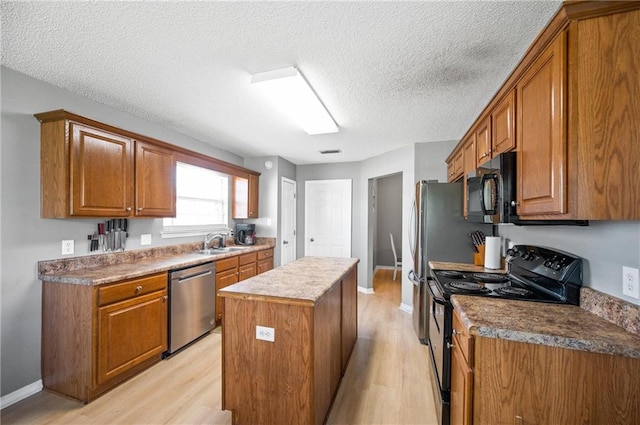 kitchen featuring light hardwood / wood-style flooring, black appliances, a textured ceiling, and a kitchen island