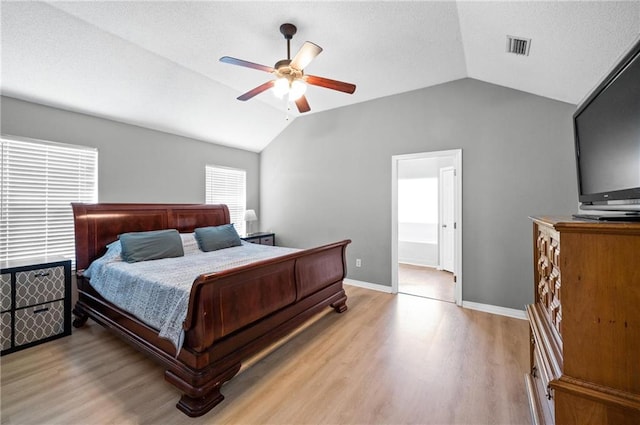 bedroom with ceiling fan, lofted ceiling, ensuite bath, and light hardwood / wood-style floors