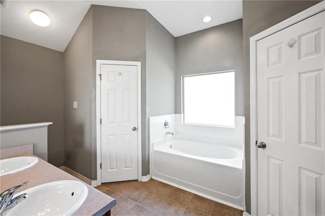 bathroom featuring a textured ceiling, tile patterned flooring, a washtub, and sink