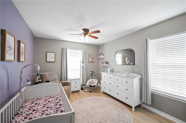 bedroom featuring light hardwood / wood-style flooring, ceiling fan, and a textured ceiling