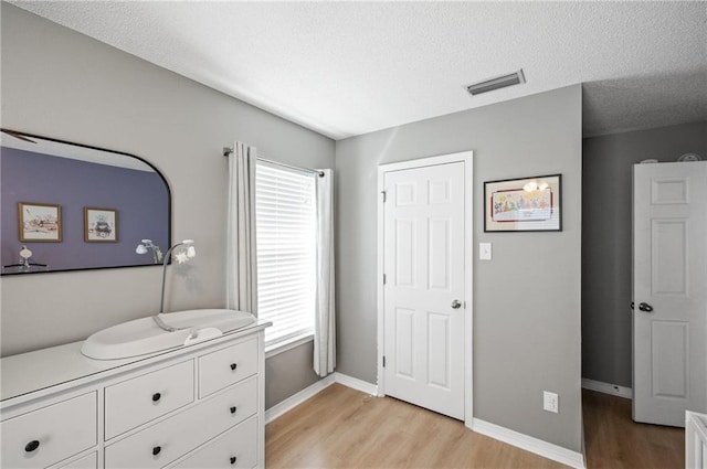 bedroom with a textured ceiling and light wood-type flooring