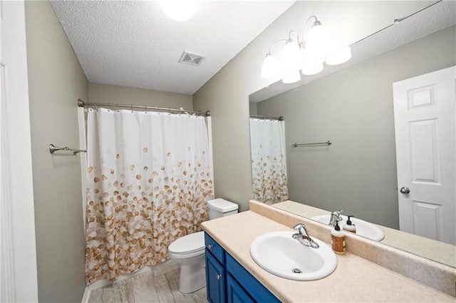 bathroom with a textured ceiling, walk in shower, vanity, and toilet