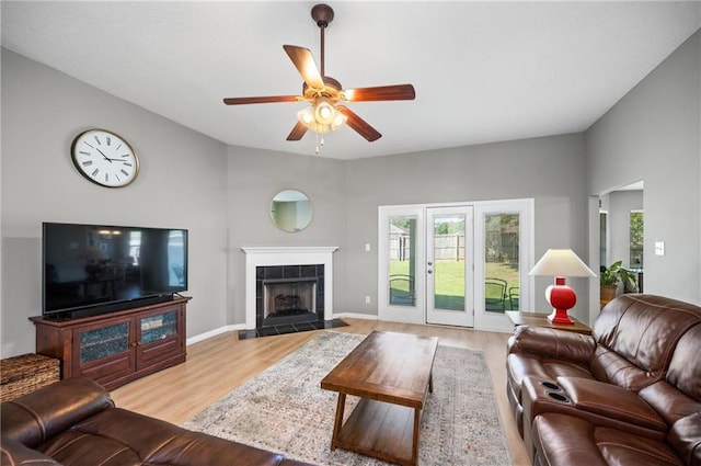 living room featuring light hardwood / wood-style flooring, ceiling fan, and a fireplace