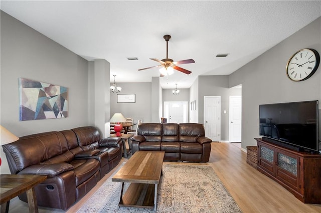 living room with light wood-type flooring and ceiling fan with notable chandelier