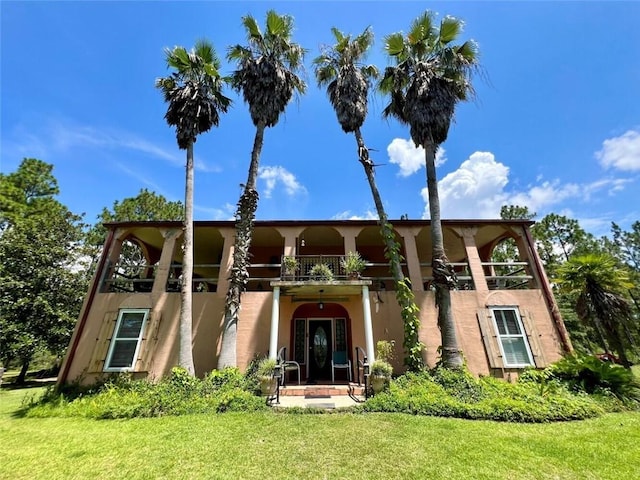 view of front of property with a balcony and a front lawn