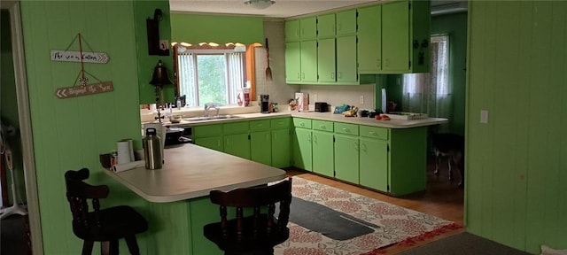 kitchen featuring hardwood / wood-style flooring, green cabinetry, a breakfast bar area, and sink