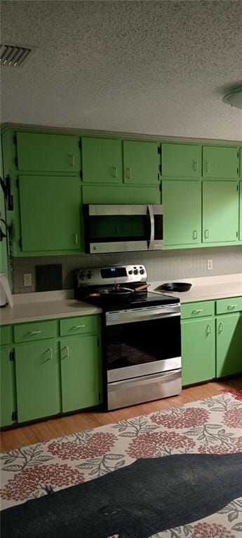 kitchen with green cabinets and appliances with stainless steel finishes