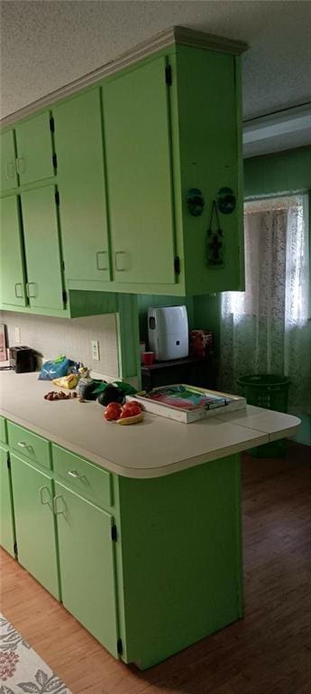 kitchen featuring light wood-type flooring, a textured ceiling, and green cabinetry