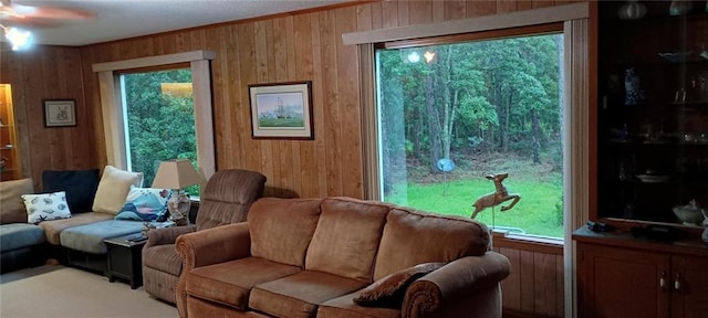 living room with plenty of natural light, wood walls, and ceiling fan