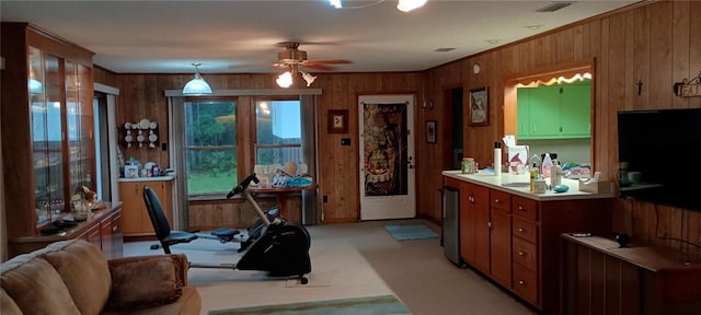 kitchen with ceiling fan, hanging light fixtures, and wooden walls