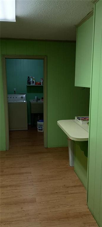 corridor with washer / dryer, a textured ceiling, and light hardwood / wood-style floors