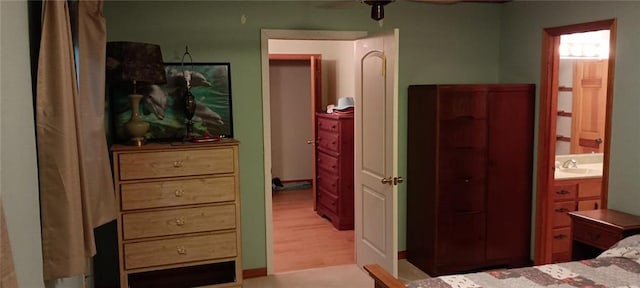 bedroom featuring connected bathroom, light hardwood / wood-style floors, and sink