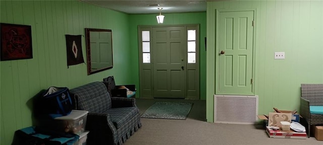 foyer entrance with carpet flooring and wooden walls