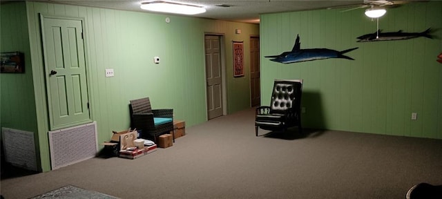 interior space with ceiling fan, carpet floors, and wooden walls