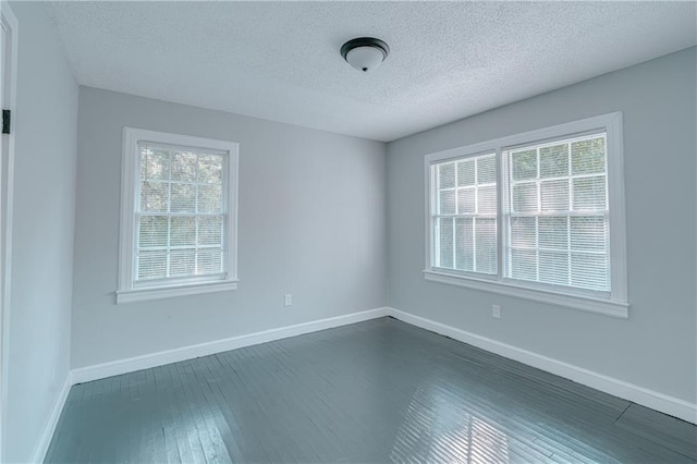 unfurnished room with a healthy amount of sunlight, dark hardwood / wood-style floors, and a textured ceiling