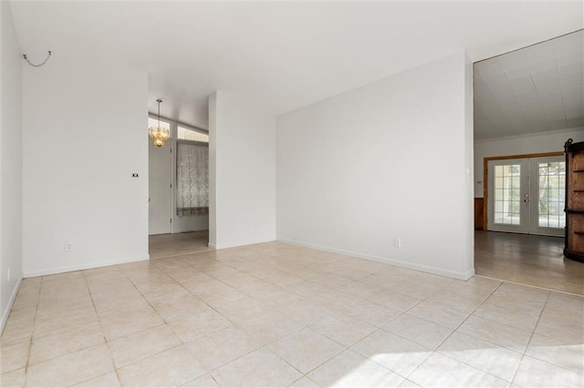 tiled spare room featuring french doors and a chandelier