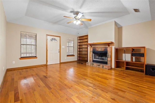 unfurnished living room featuring ceiling fan, light hardwood / wood-style floors, a raised ceiling, and a textured ceiling