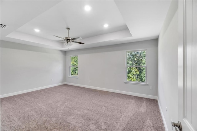 empty room with carpet, ceiling fan, and a tray ceiling