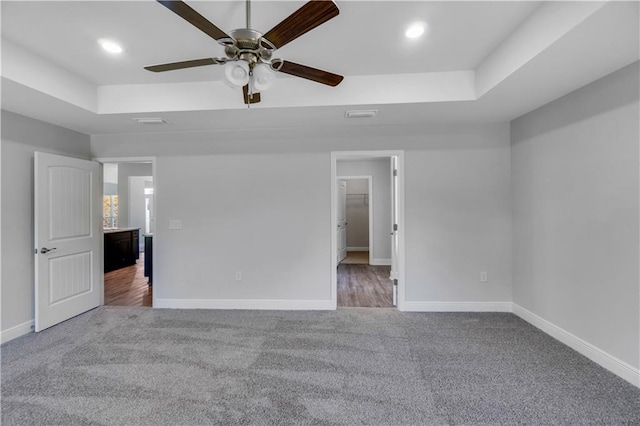 unfurnished bedroom with a raised ceiling, carpet, and ceiling fan